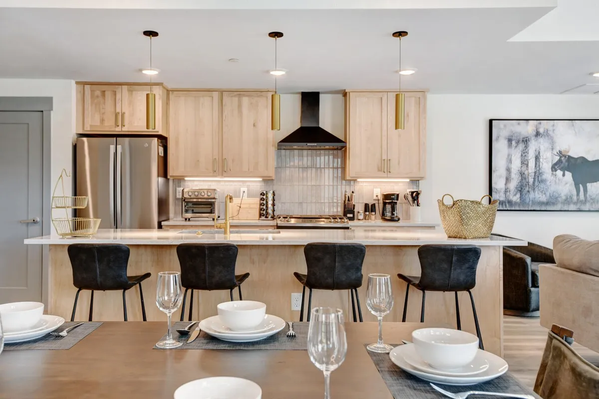 A bright, inviting kitchen with a central island surrounded by bar stools, modern appliances, and tasteful decorative artwork on the walls. The layout encourages casual dining, entertaining, and socializing while preparing meals.