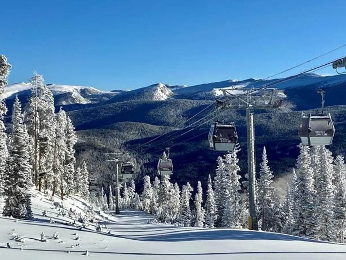 A vibrant winter scene featuring a ski lift ascending the snowy mountains, framed by snow-laden trees and a bright blue sky. The landscape conveys the excitement of skiing, snowboarding, and other winter sports, while the ski lift points to easy resort access.