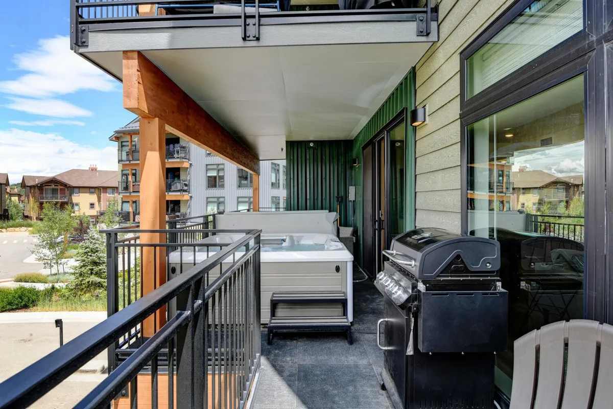 This view features an exterior balcony with a hot tub, grill, and relaxing seating. The setup encourages outdoor dining, relaxation, and family bonding, with picturesque views that invite guests to make the most of the outdoor space.