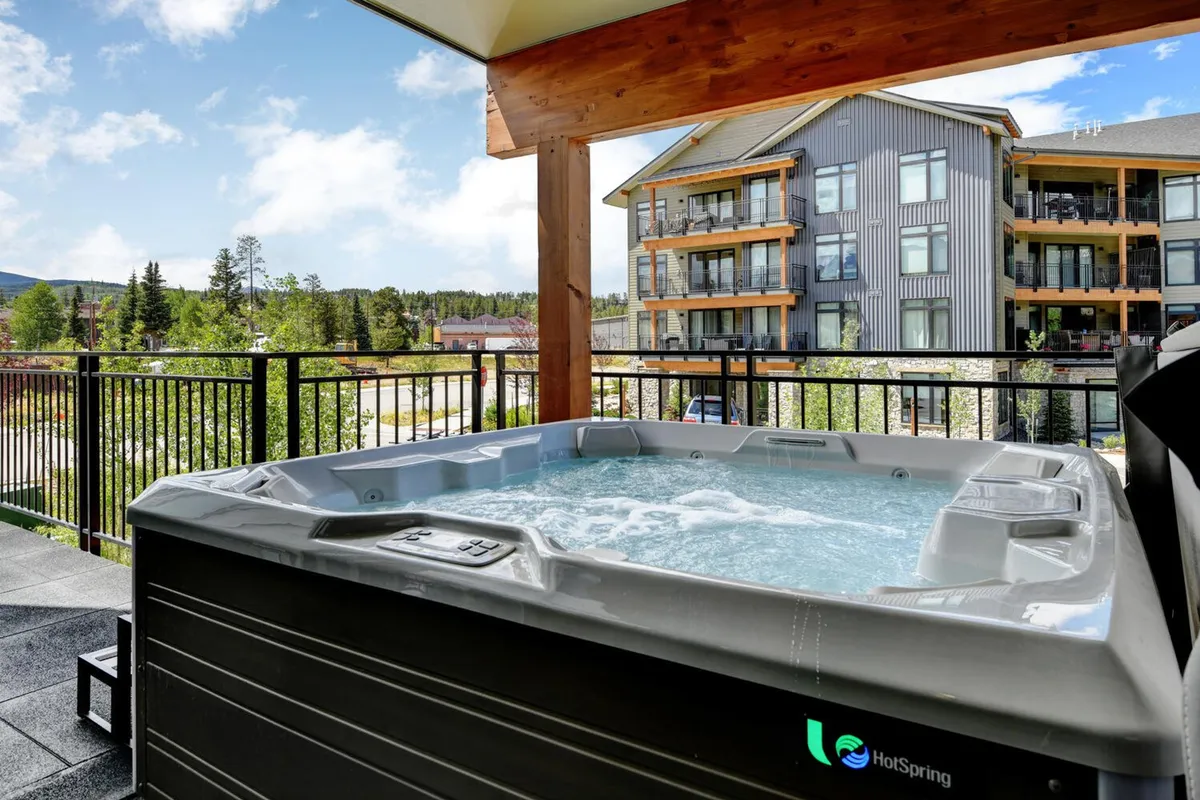 This exterior image showcases the private hot tub set against a scenic natural backdrop and the building's exterior. The inviting setting encourages relaxation and family bonding after a day of local adventures. The hot tub is positioned to provide sunset views and opportunities for star gazing, emphasizing outdoor fun and comfort.