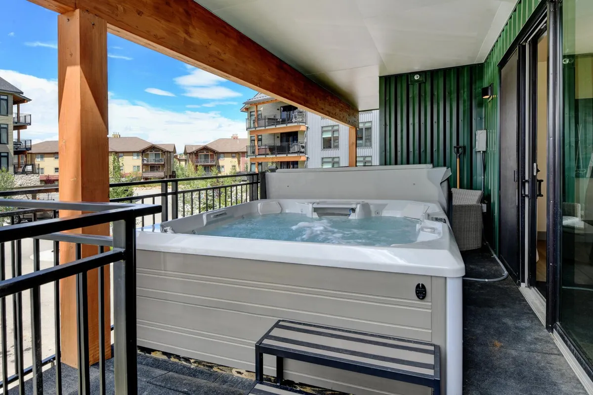 An inviting outdoor community hot tub surrounded by comfortable seating and wooden beams, with tranquil views in the background. The scene evokes relaxation and the social, resort-style amenities available to residents and guests.