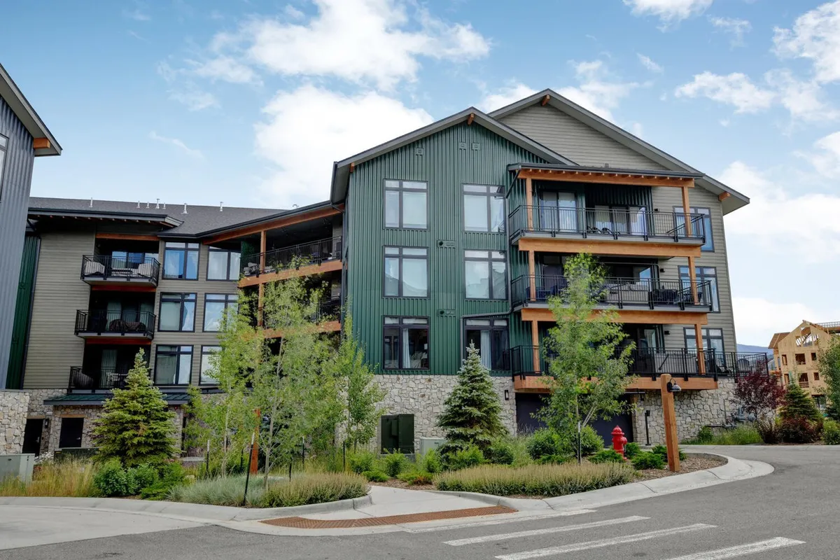 The image highlights the modern exterior design of the condo, complemented by wooden balconies and landscaped gardens. People can be seen enjoying the views from balconies and walking through the gardens, conveying a sense of community and connection to outdoor spaces.